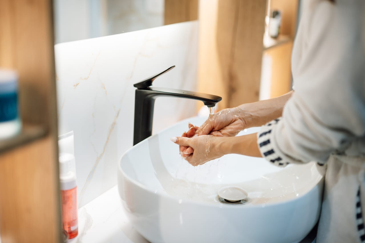 Hands washing at a bathroom basin and single-lever faucet