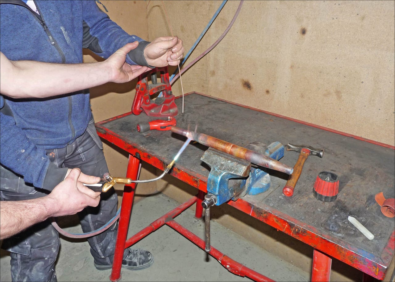 Heating a copper-pipe joint at a workshop bench