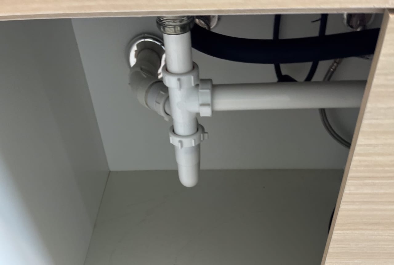 Accessible PVC trap and waste-pipe connections beneath a sink